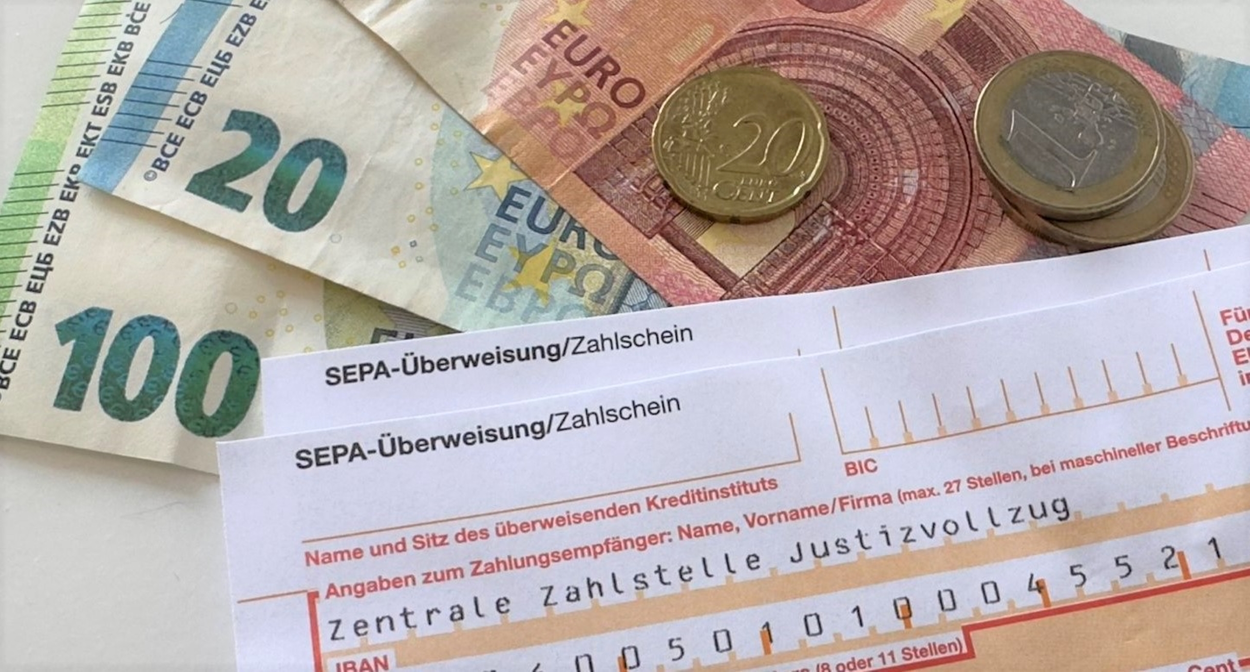 Geld und ein Überweisungsträger liegen auf einem Tisch. 